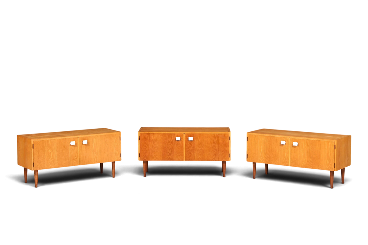 Hauptstadt Möblerei Hellerau Modell 427 Mid Century Sideboards aus hellem Holz mit weißen Griffen vor grauer Wand